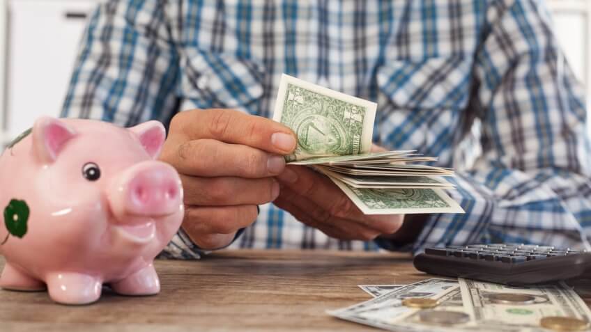 Senior man counting money with calculator.