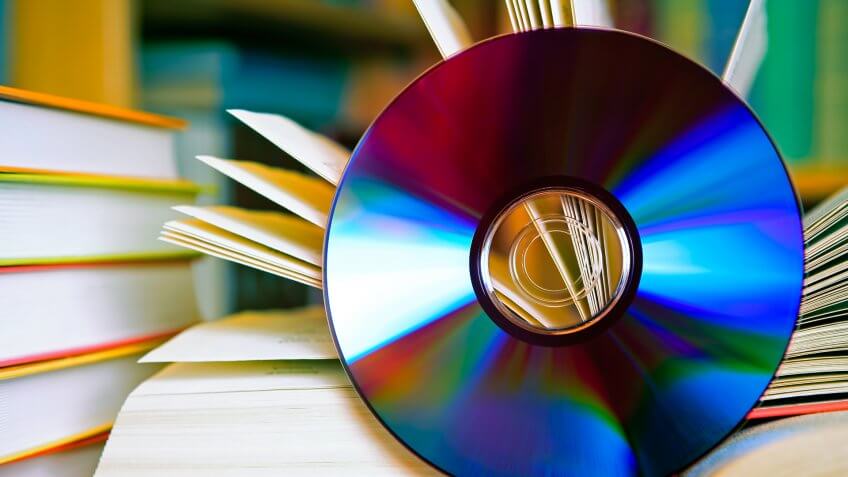 A DSLR photo of an open book with a CD in front of it.