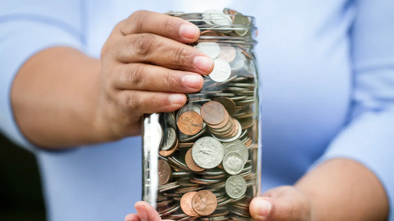 Woman holding a jar of money.