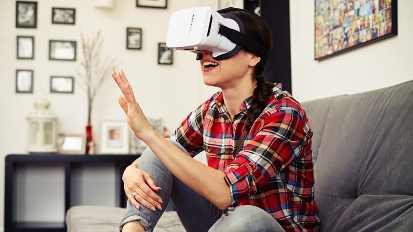 Woman wearing 8i VR goggles on a couch with her hand in the air
