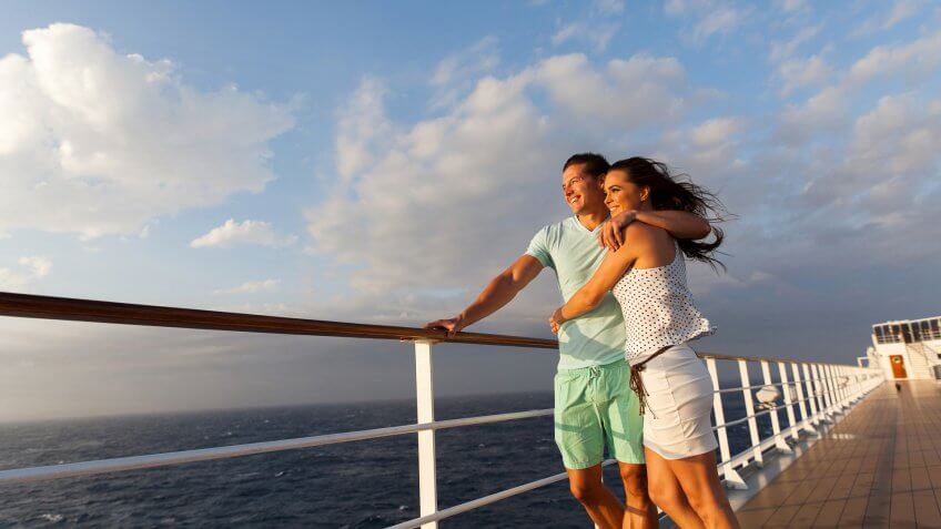 loving married couple standing on cruise deck enjoying sunset together.