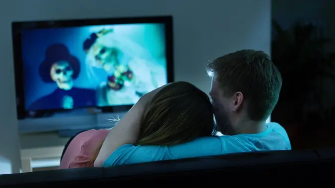 Couple watching Scary Halloween horror movie on TV together at home.