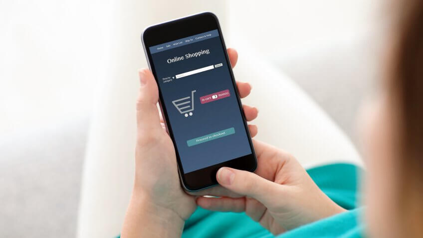 woman sitting on a sofa and makes online shopping on a tablet.