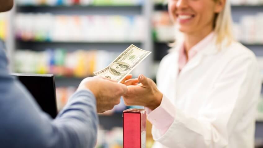 Unrecognizable customer paying with cash in pharmacy.