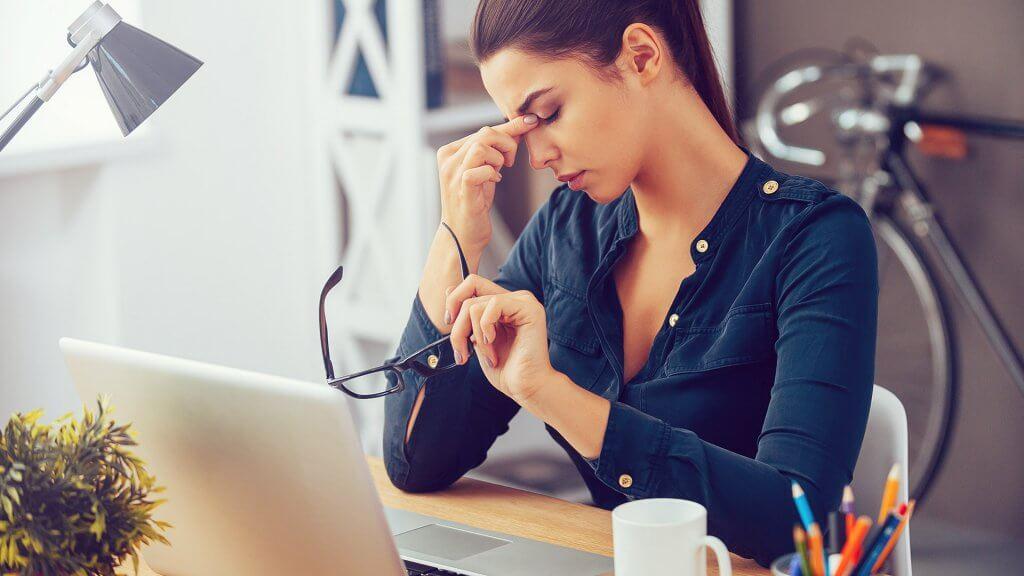 woman taking off glasses frustrated at work
