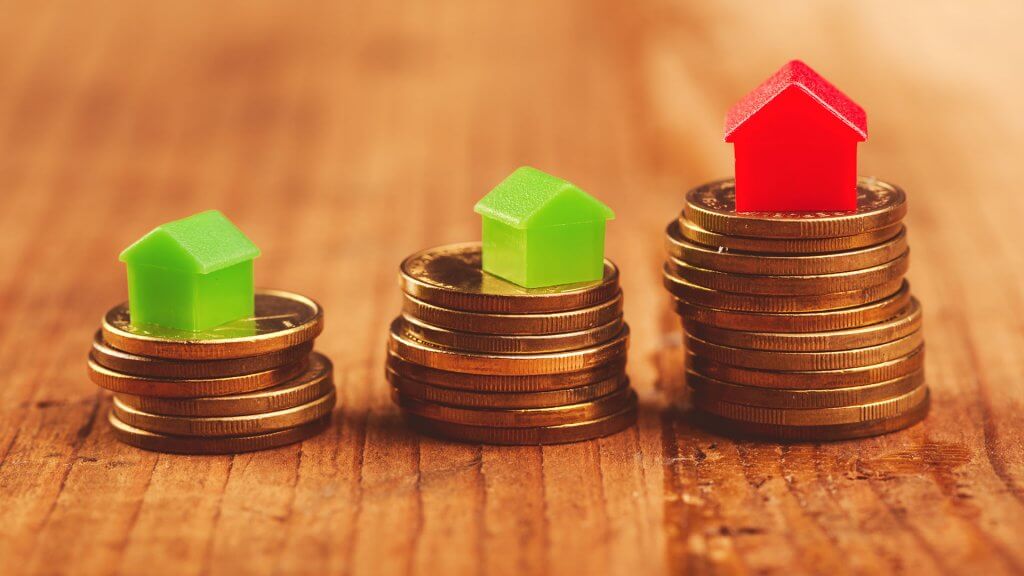 Homes are typically a good investment. stacks of coins with tiny plastic houses on top of them