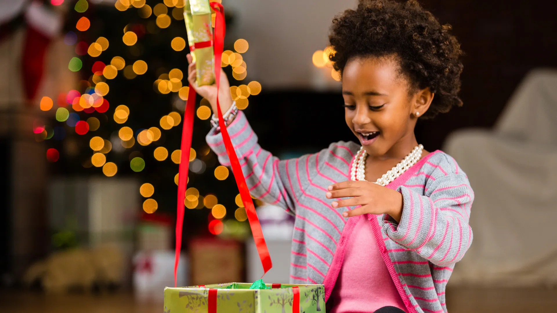 African American preschool girl opening Christmas present.