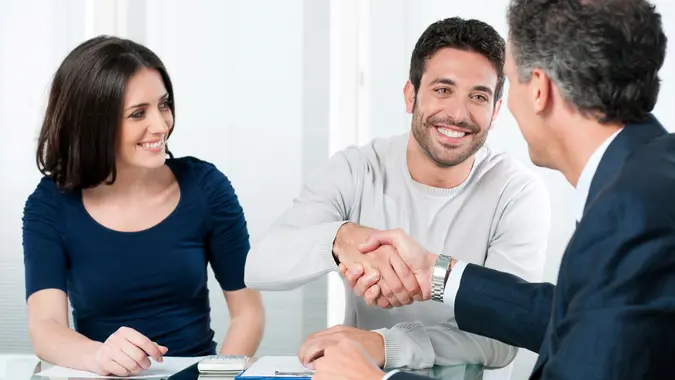 Happy couple seal a deal with their personal financial advisor at home.