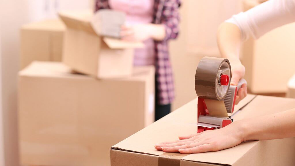 Move in the winter. person taping up moving boxes