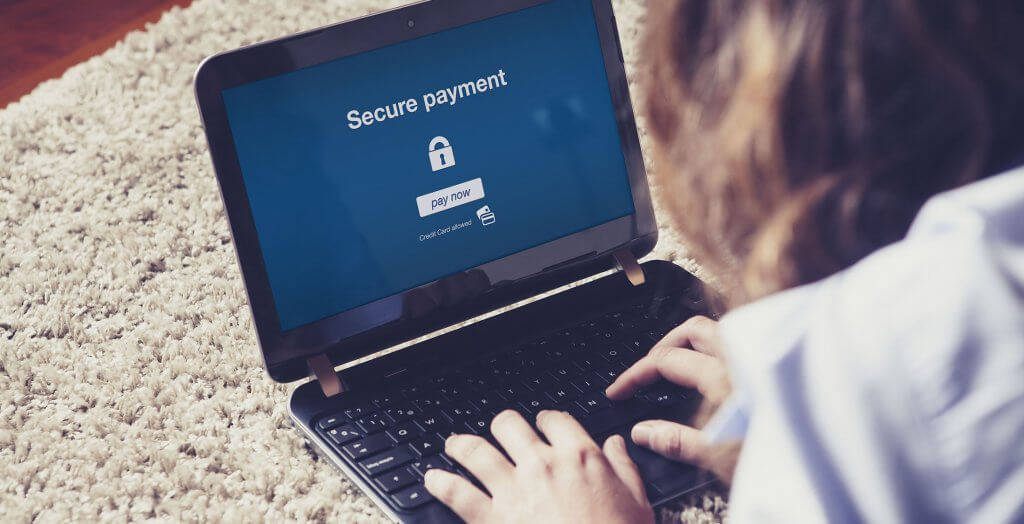 Online fraud is more prevalent. woman on laptop on floor paying a secure payment