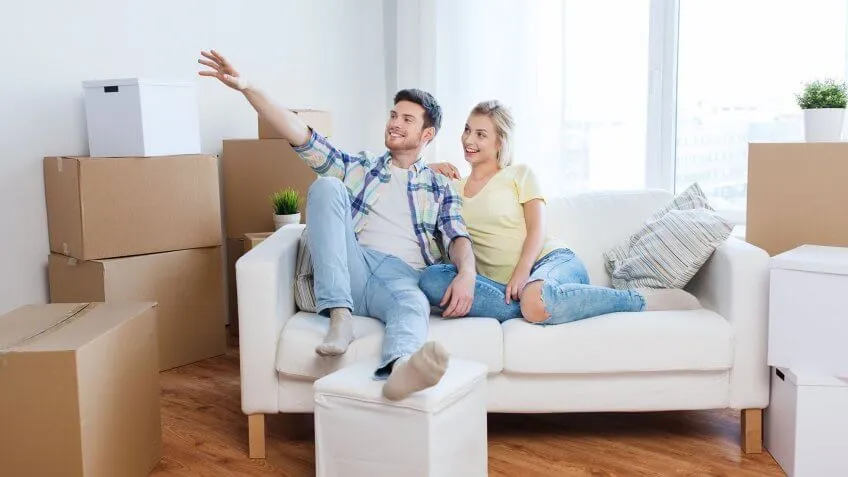couple sitting on couch with moving boxes all around them
