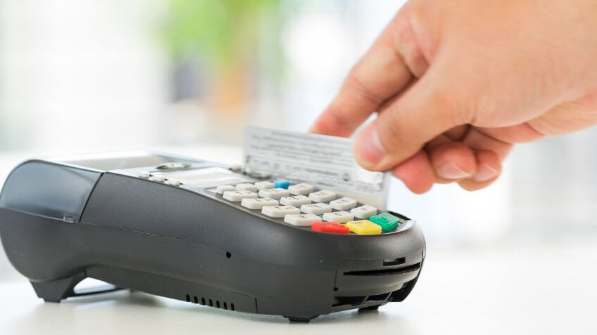 Higher-income adults have more credit card debt. person swiping credit card