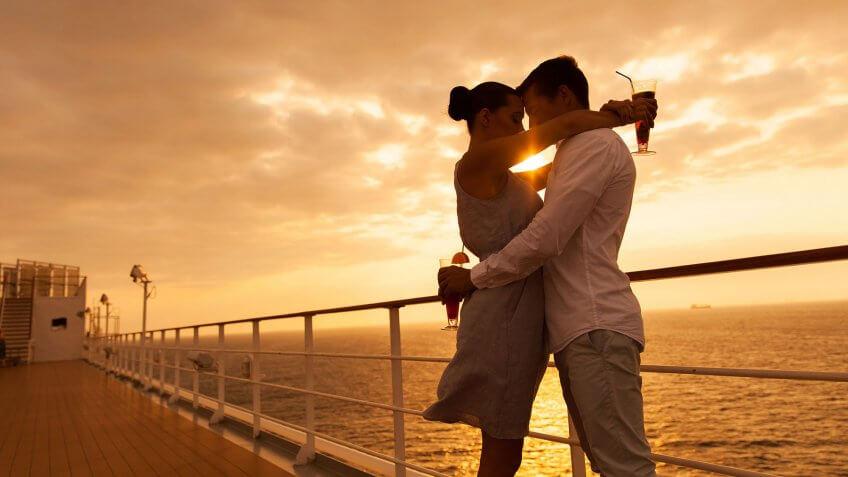 couple on cruise hugging with drinks at sunset