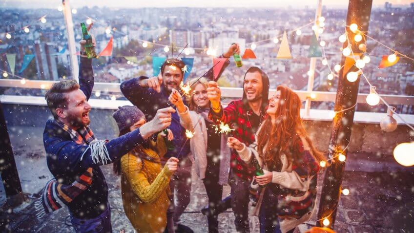Couple of friends having a party on the rooftop of the building while snowing.