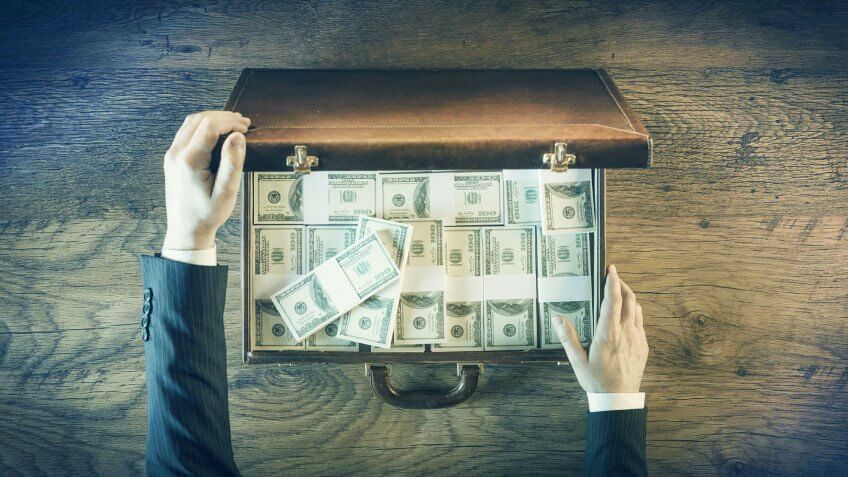 You think money is evil. man opening a suitcase full of cash
