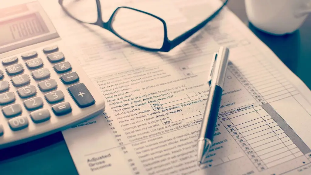 pen glasses and calculator on top of tax form