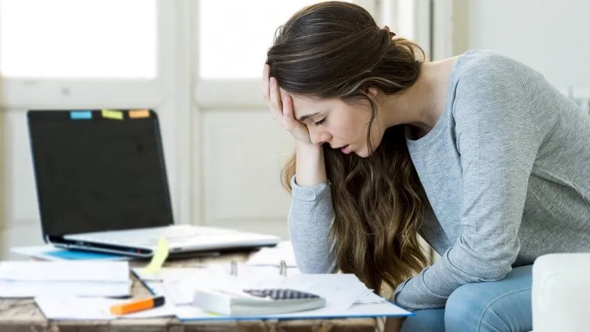 stressed woman hunched over pile of work