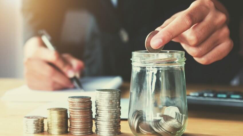 Saving money woman hand putting coin in jug glass concept business finance.