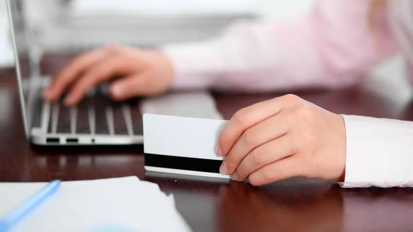person on laptop with card in hand