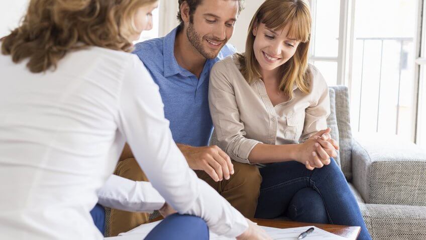 Use your words to ask for cheaper rent. couple reviewing documents on table with third person