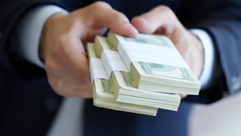 Pay upfront. man holding stacks of $100 bills