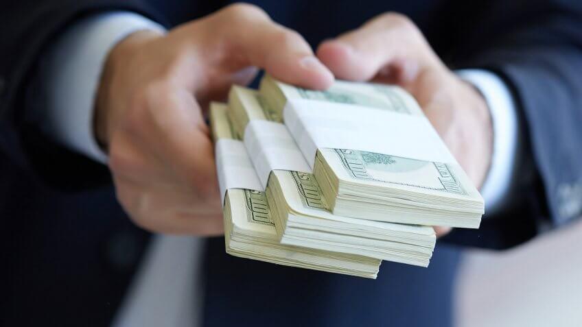 man holding stacks of $100 bills
