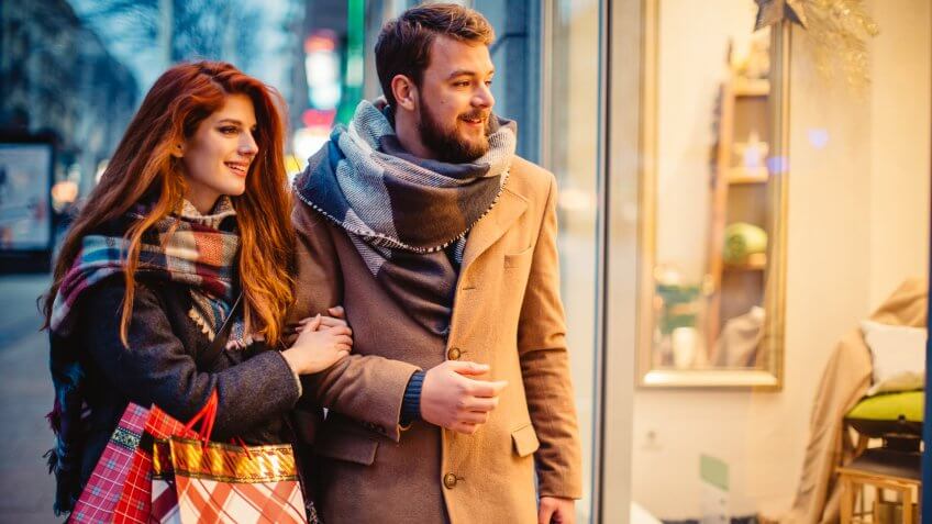 Couple window shopping outdoors in winter city street.