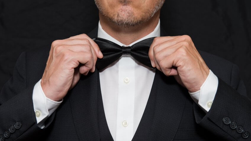 man pulling bowtie on tuxedo