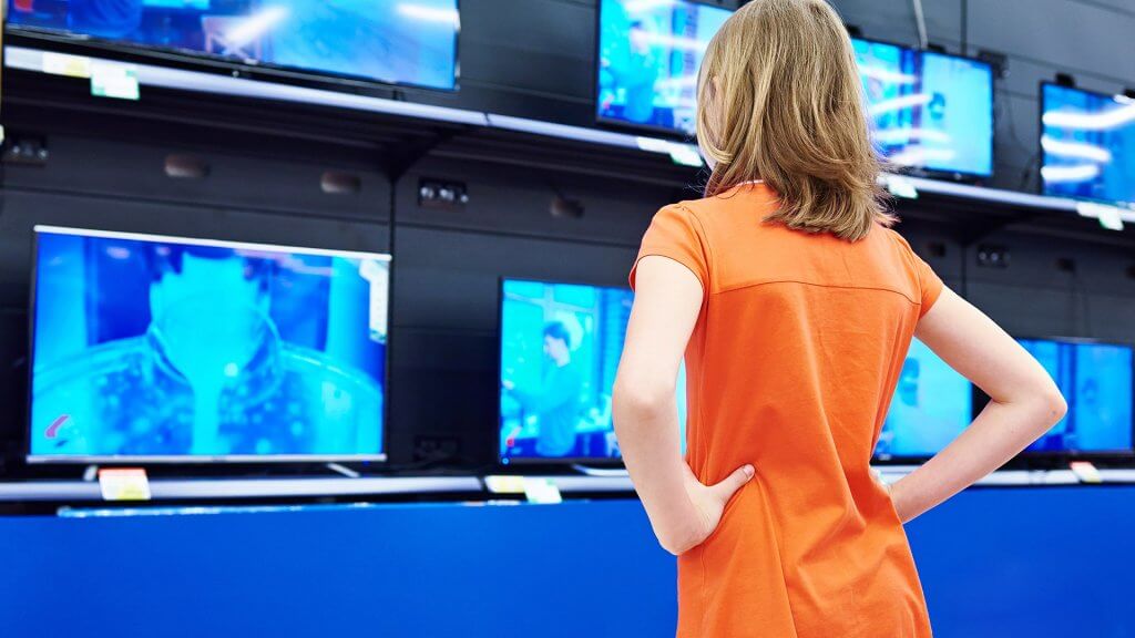 Electronics are the best items to buy during Black Friday sales. woman in orange dress shopping for TVs