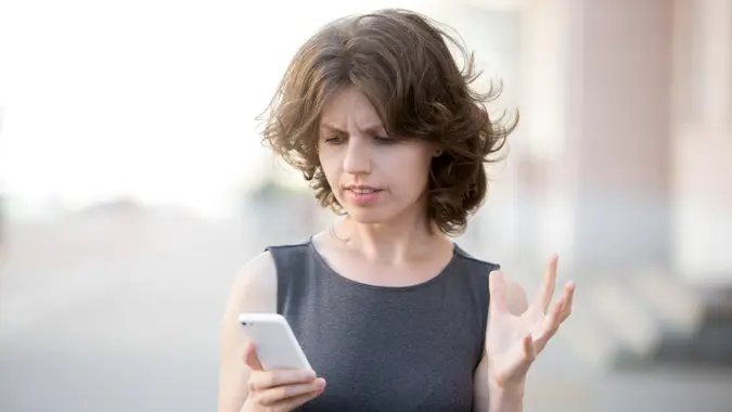 Portrait of young woman holding cellphone in hands