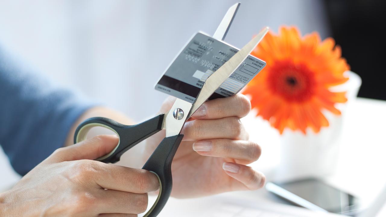 Female hands cutting a credit card with scissors.