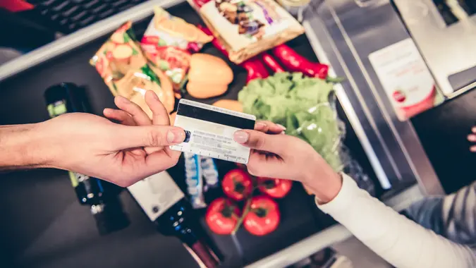 Cropped image of handsome man giving a credit card at the cash desk in the supermarket.