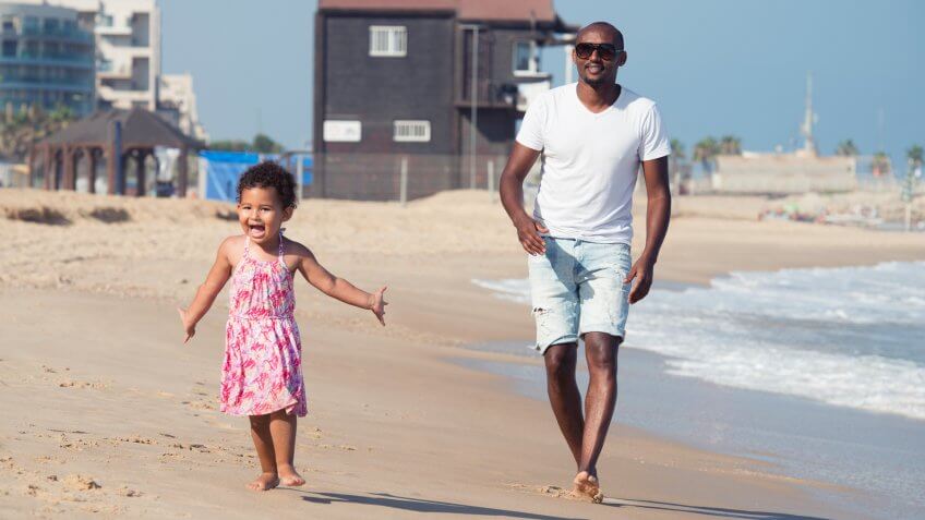 2 years baby girl playing together with her uncle at the beach, walking exited on seacoast.