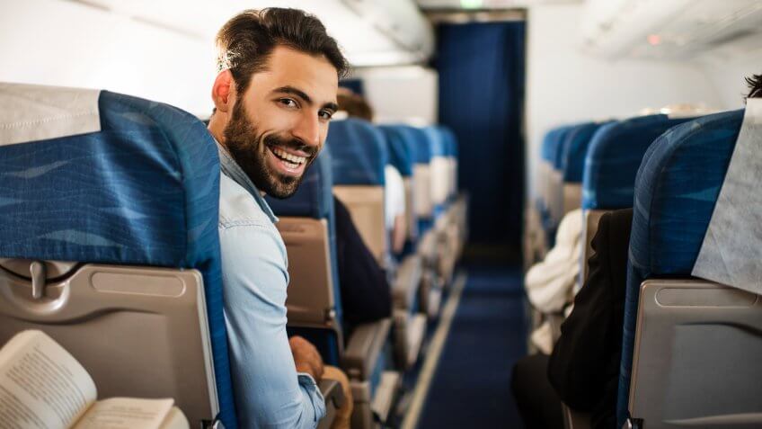 Happy passenger flying by airplane and turning towards the camera.