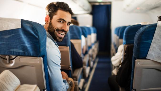 Happy passenger flying by airplane and turning towards the camera.