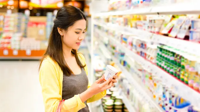Asian woman buys in the supermarket yogurt.