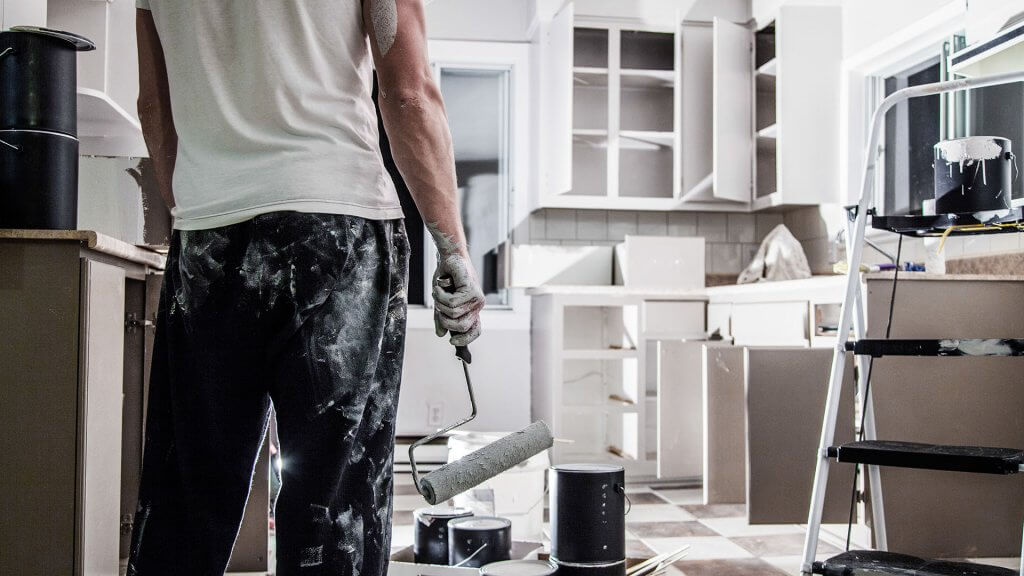 A kitchen upgrade is a good investment. man covered in white paint painting kitchen white