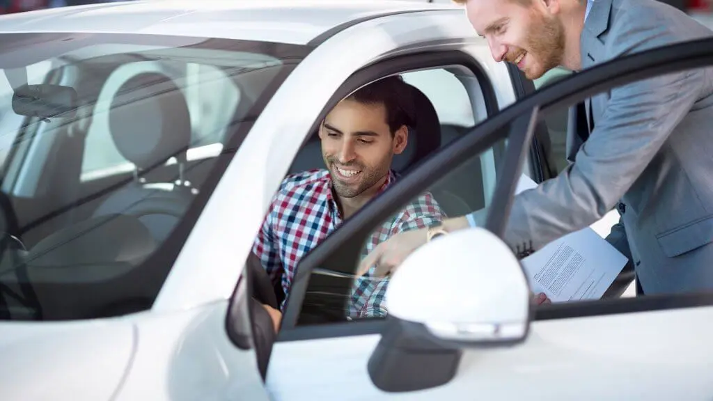 car salesman showing car to man