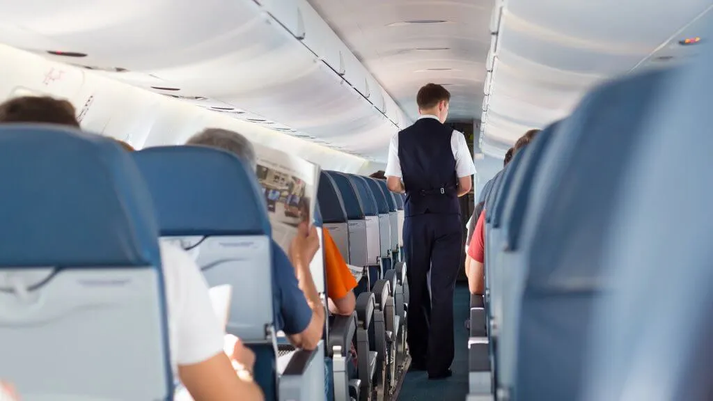 inside of plane with flight attendant walking down aisle