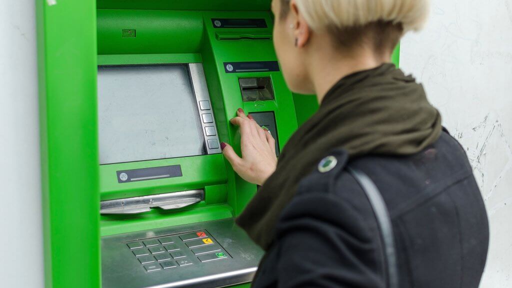 Bank Fees. woman using green atm