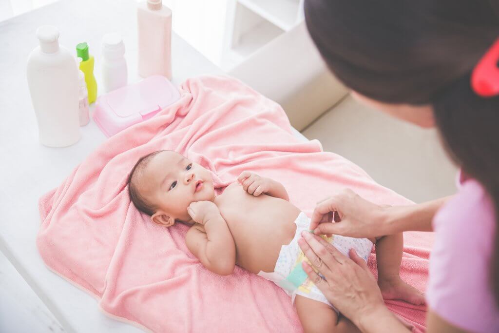 Purchasing Expensive Diapers woman changing baby diaper