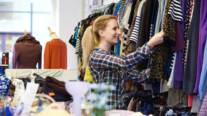 Female Shopper In Thrift Store Looking At Clothes