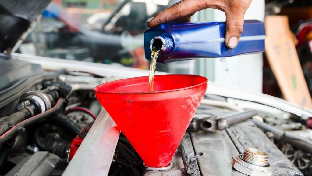 person pouring oil into car