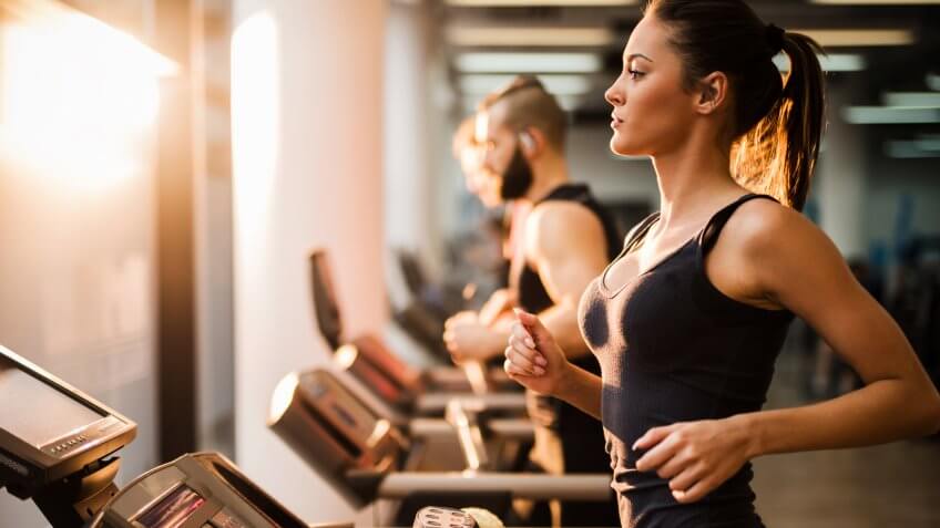 Young people exercising in a gym on treadmill