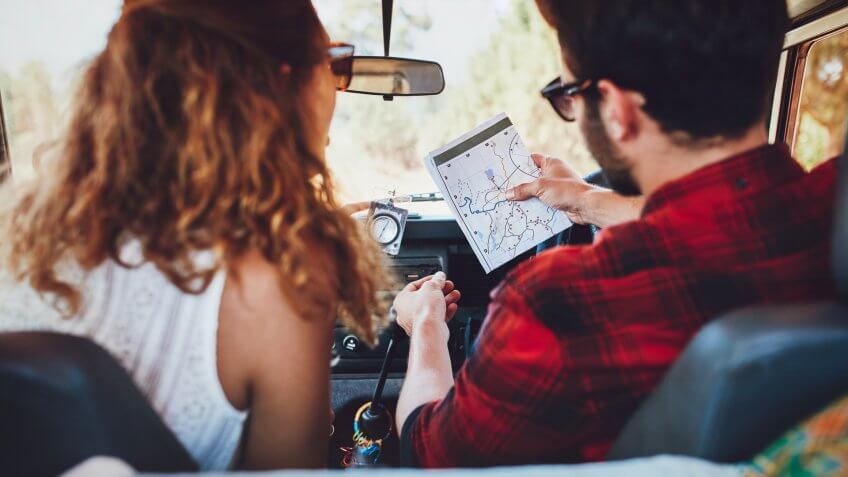 Rear view of a young couple in their car checking a map