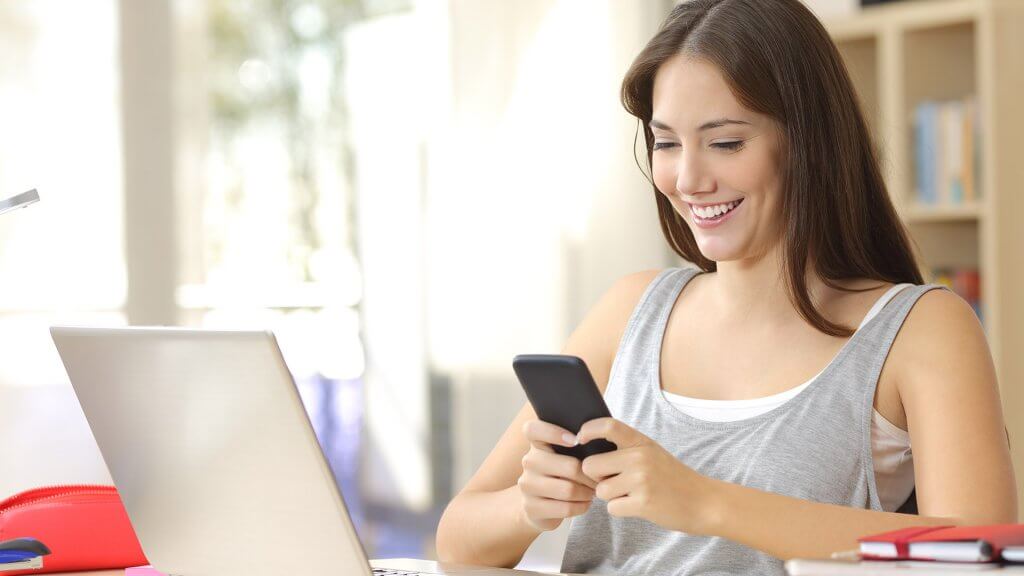 Research discounts online. woman on phone and laptop