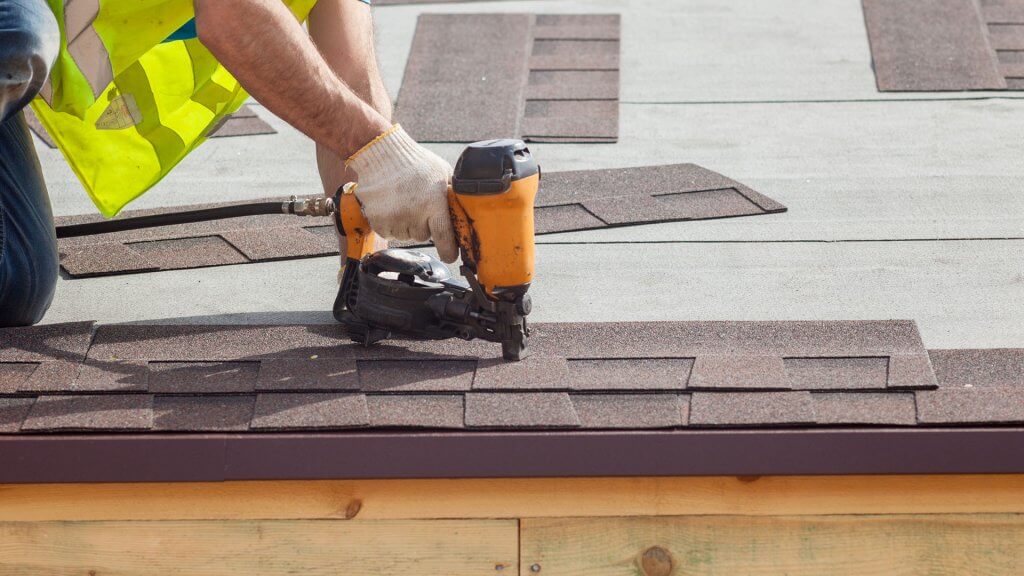 A new roof is almost always a good investment. roofer applying shingles with power tool