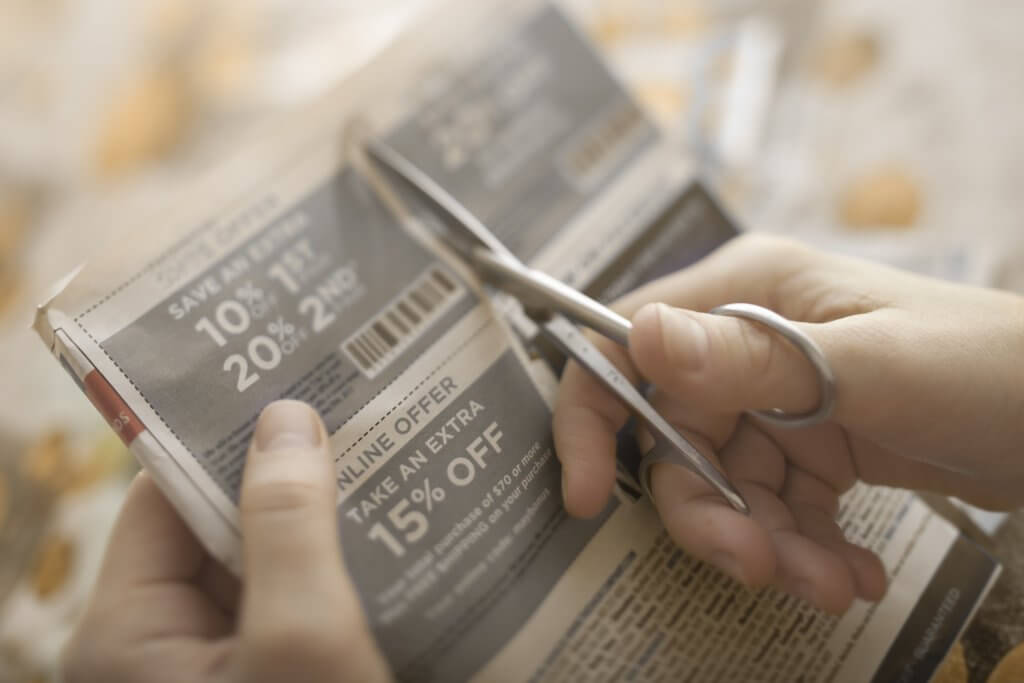 Failing to Shop for Bargains person cutting out coupon