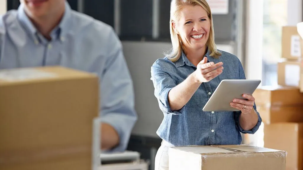 woman with tablet in room full of moving boxes