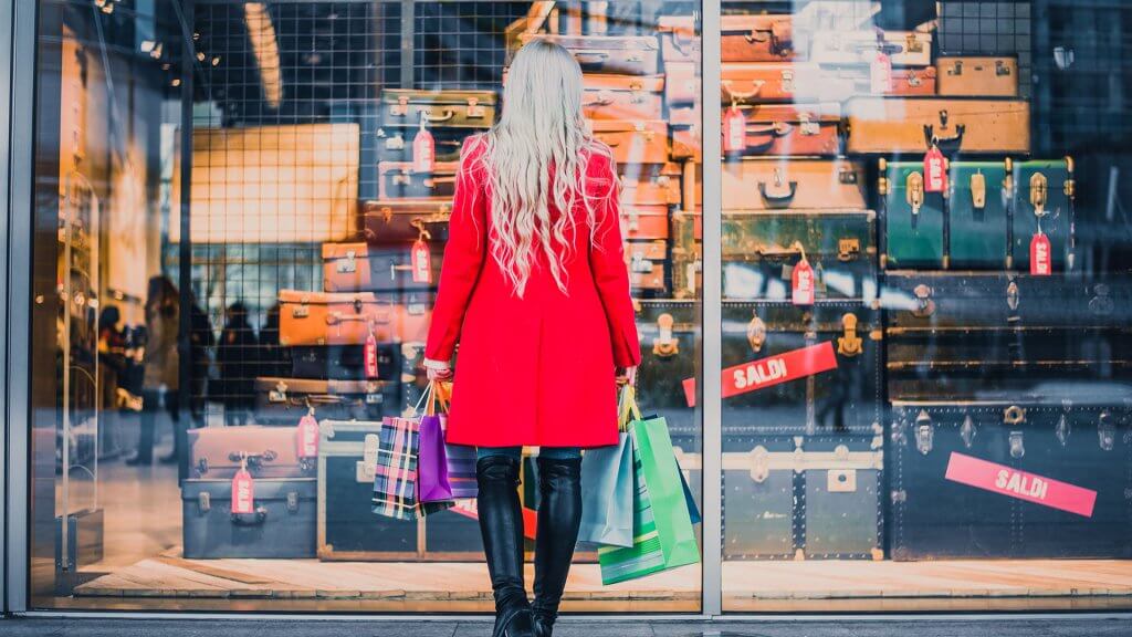 Be Careful Where You Shop woman with shopping bags and standing in front of store window